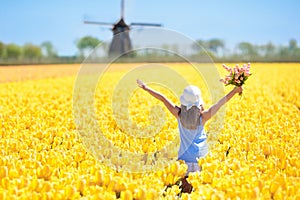 Kids in tulip flower field. Windmill in Holland