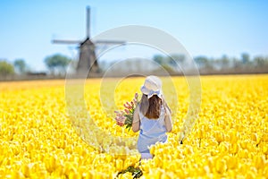 Kids in tulip flower field. Windmill in Holland