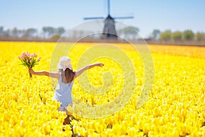 Kids in tulip flower field. Windmill in Holland