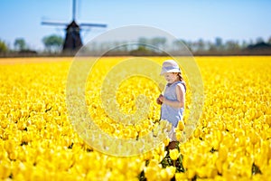 Kids in tulip flower field. Windmill in Holland