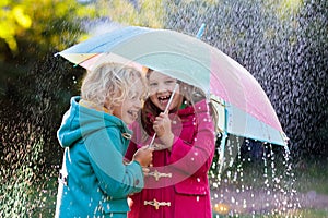 Kids with umbrella playing in autumn shower rain