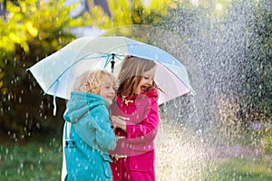 Kids with umbrella playing in autumn shower rain