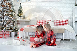 Kids unwrap gifts from Santa sitting by the bed on Christmas morning