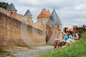Kids on vacation in Carcassonne, point at towers sit and rest