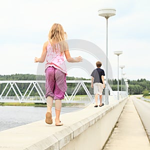 Kids walking on railing of dam