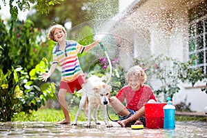 Kids wash dog in summer garden. Water hose fun