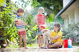 Kids wash dog in summer garden. Water hose fun