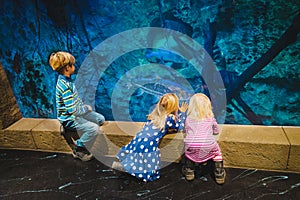 Kids watching fishes in aquarium, learning marine life