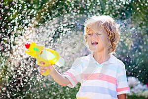 Kids with water gun toy in garden. Outdoor fun