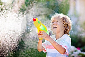 Kids with water gun toy in garden. Outdoor fun