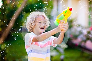 Kids with water gun toy in garden. Outdoor fun