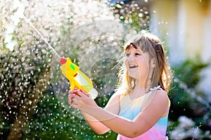 Kids with water gun toy in garden. Outdoor fun
