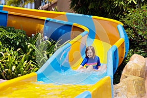 Kids on water slide in aqua park. Summer vacation