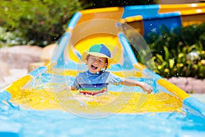 Kids on water slide in aqua park. Summer vacation