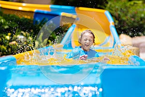 Kids on water slide in aqua park. Summer vacation