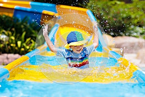 Kids on water slide in aqua park. Summer vacation