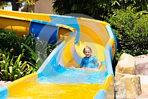 Kids on water slide in aqua park. Summer vacation