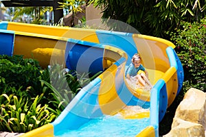 Kids on water slide in aqua park. Summer vacation