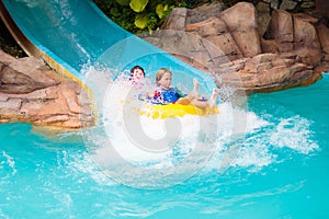 Kids on water slide. Family in aqua theme park