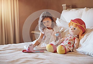 Kids will be kids. an adorable little girl pretending to have a tea party with her doll at home.