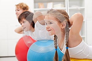 Kids and woman doing exercises with balls