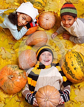 Kids among yellow leaves and orange pumpkings