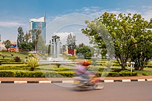 Kigali, Rwanda - September 20, 2018: A `moto` motorbike at a roundabout near the city centre, with Kigali City Tower in the back