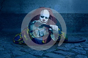 A killer clown with a knife rising from the sewer photo