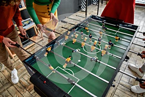 Killing boredom. Cropped photo of young people playing table soccer in the office. Having fun after work