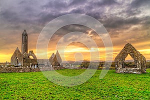 Kilmacduagh monastery with stone tower at sunset