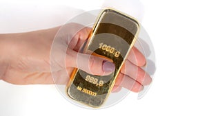 A kilogram ingot of gold in a woman`s hand isolated on white