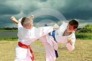 In the kimono two athletes are hitting arm and leg on the background stormy sky