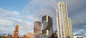 Kimpton Clock Tower in Manchester with adjacent skycrapper buildings create a parralel geometric scenery with a sunny sky