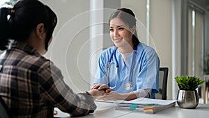 A kind Asian female doctor holds a patient's hands to reassure and comfort her feelings