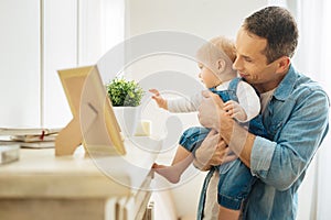 Kind attentive father showing his baby different items on the fireplace