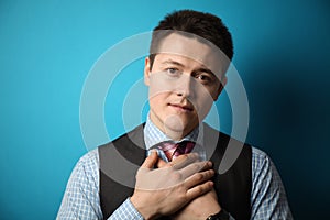 Kind look of a young man in a suit on a blue background. Prayer and redemption of gruhs. Donation