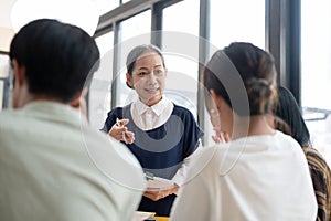 A kind mature Asian female professor is giving a lecture to her students in the classroom