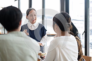 A kind mature Asian female professor is giving a lecture to her students in the classroom