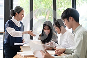 A kind mature Asian female professor is giving a lecture to her students in the classroom