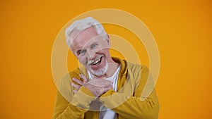 Kind old person crossing palms on breast, smiling to camera, sincerity concept