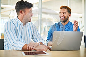 The kind of teammates that keep tasks on track. two young businessmen having a meeting in a modern office.