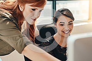 The kind of teamwork responsible for getting results. two young businesswomen using a computer together in a modern