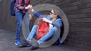 Kind teenage student giving helping hand to bullied nerd boy, supportive friend photo