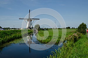 Kinderdijk, The Netherlands, August 2019. Postcard image of Holland: a white windmill is mirrored on the water channel in front of