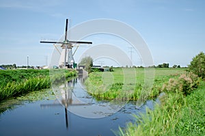 Kinderdijk, The Netherlands, August 2019. Postcard image of Holland: a white windmill is mirrored on the water channel in front of