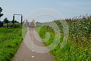 Kinderdijk, The Netherlands, August 2019. A small road winds through the Dutch countryside, lined with green grass and a canal, in