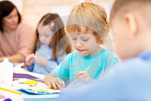 Kindergarten children doing arts and crafts with teacher in day care centre