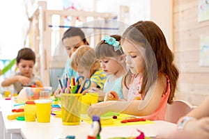 Kindergarten kids doing arts and crafts with teacher in day care centre