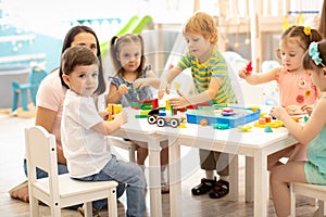 Kindergarten children playing toys with teacher in playroom at preschool. Education concept.