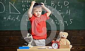 Kindergarten graduation concept. Kid boy in graduate cap ready to go to school, chalkboard on background. Child, pupil